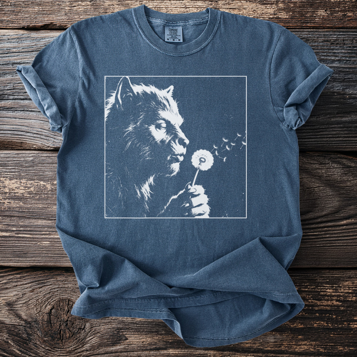 Werewolf blowing on a dandelion, white graphic on blue t-shirt.