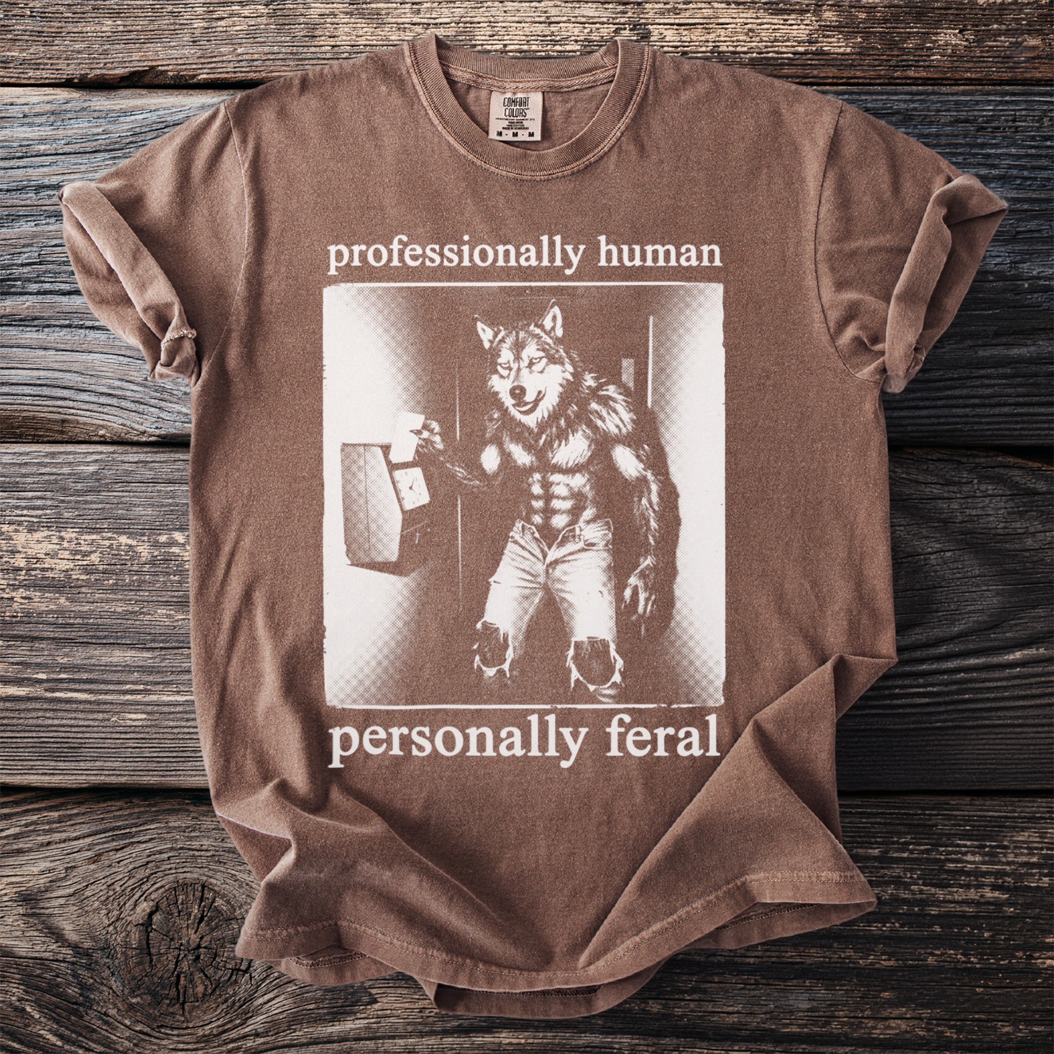 Brown t-shirt with werewolf graphic and text "professionally human personally feral".