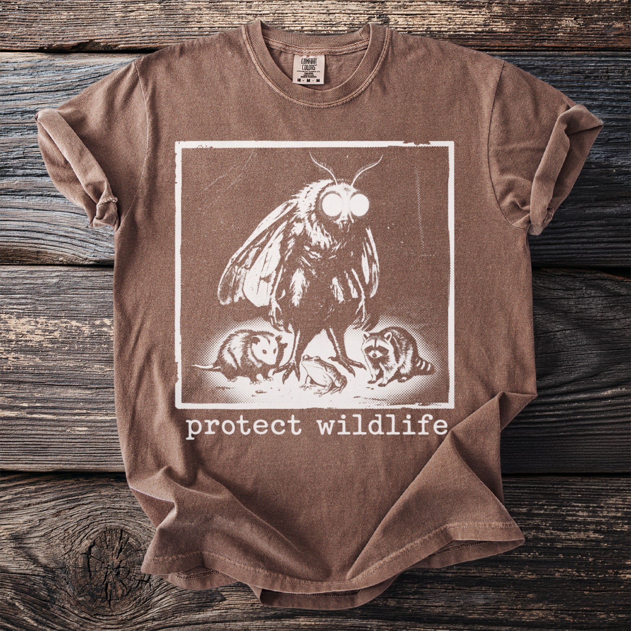Brown t-shirt with a moth, opossum, frog, and raccoon graphic and "protect wildlife" text.