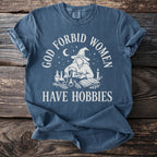 Blue t-shirt with white text and graphics of a witch, potions, and books.
