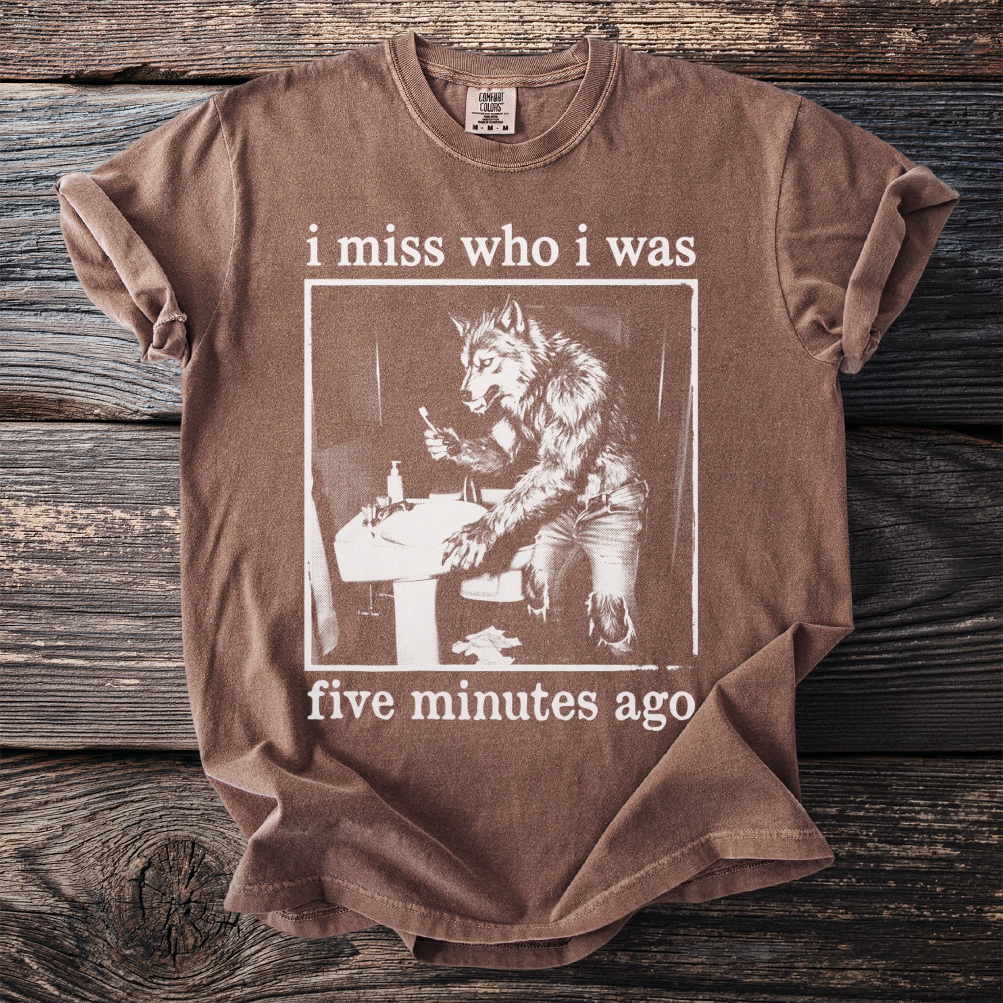 Brown t-shirt with werewolf at sink graphic and text "i miss who i was five minutes ago".
