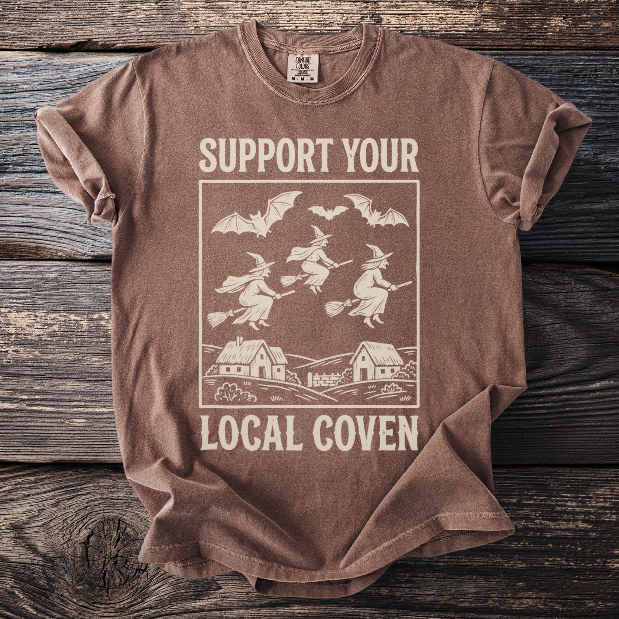 Brown t-shirt with "SUPPORT YOUR LOCAL COVEN" text and witch graphic.