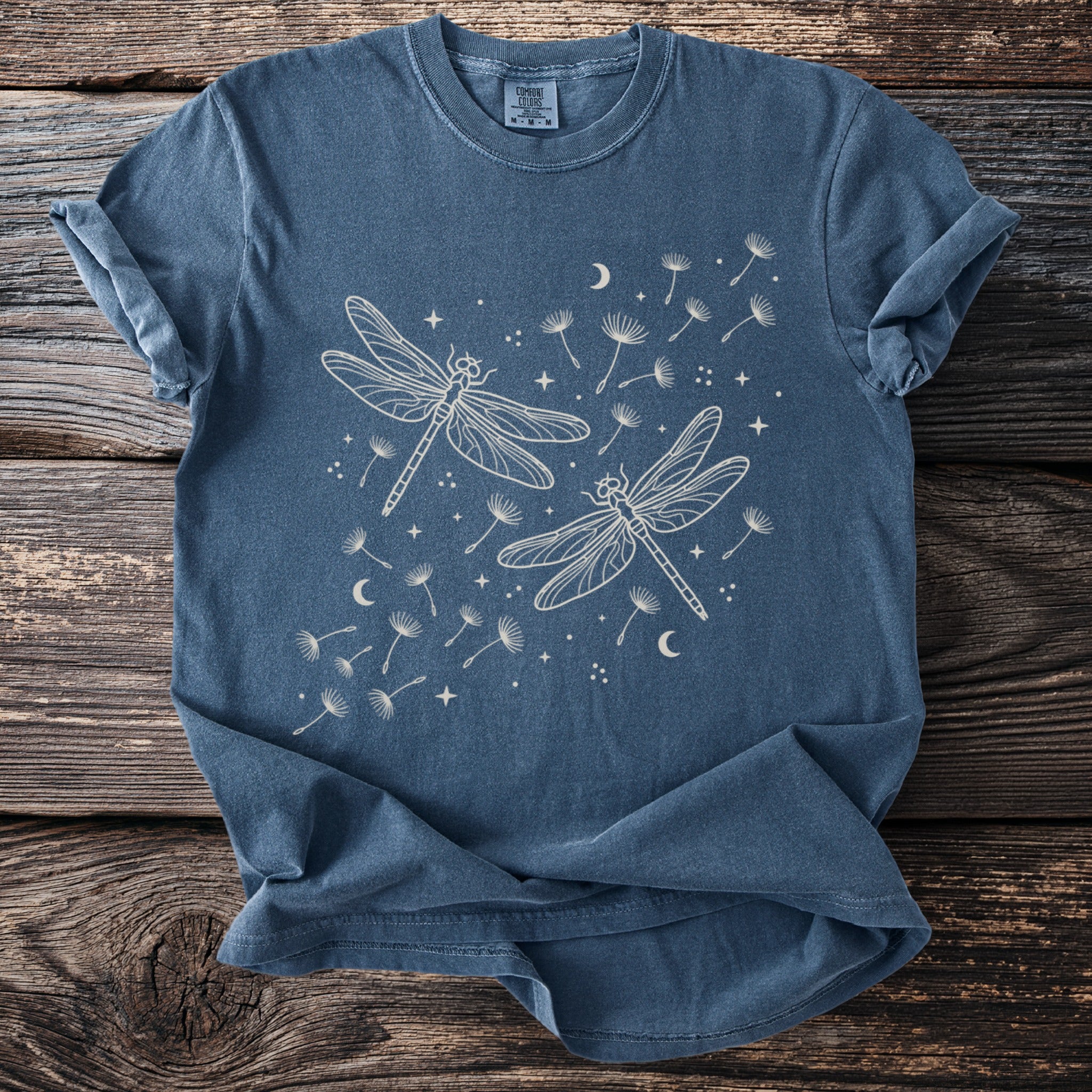 Blue t-shirt with white line drawing of two dragonflies and dandelion seeds.