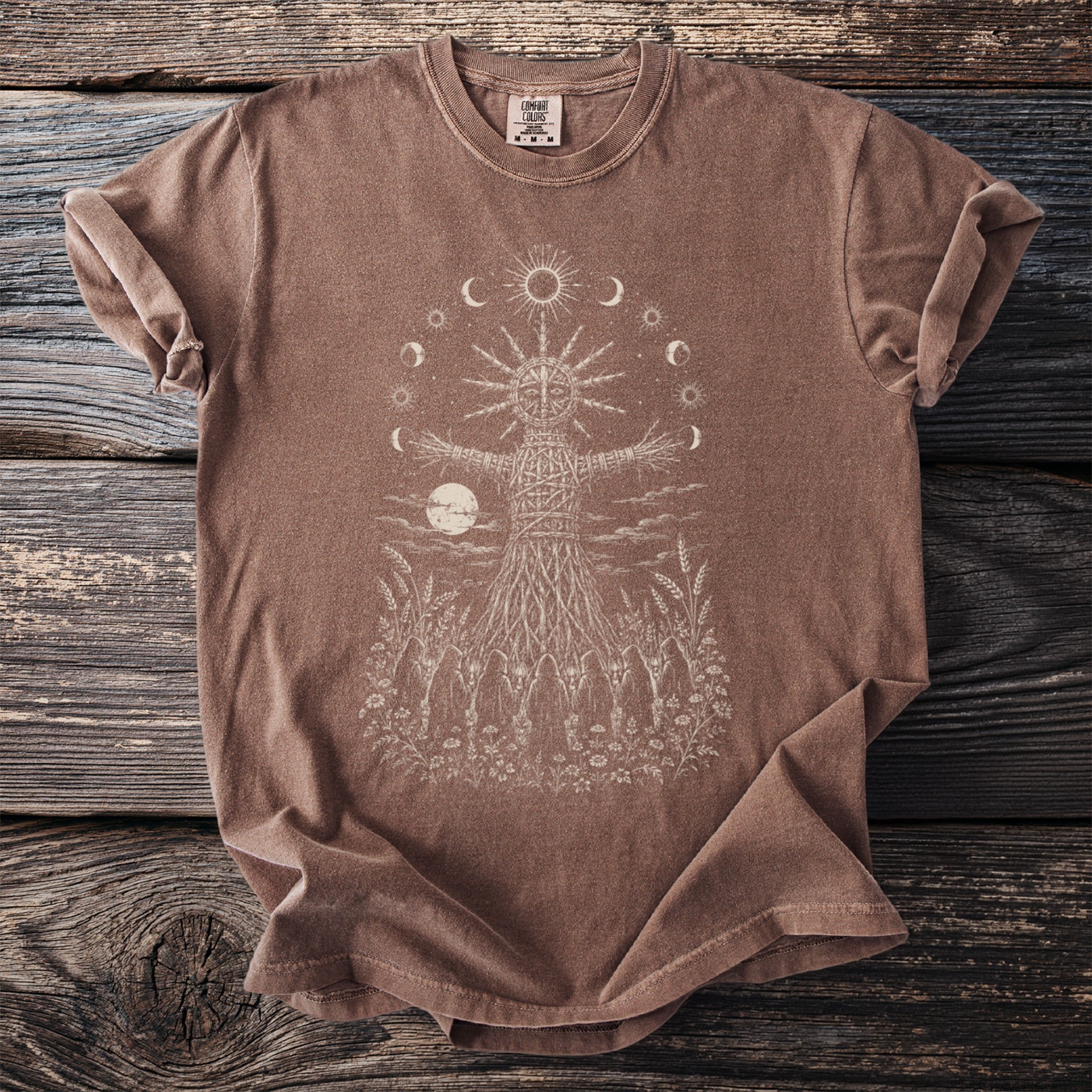 Brown t-shirt with a sun, moon cycle, and figure design.
