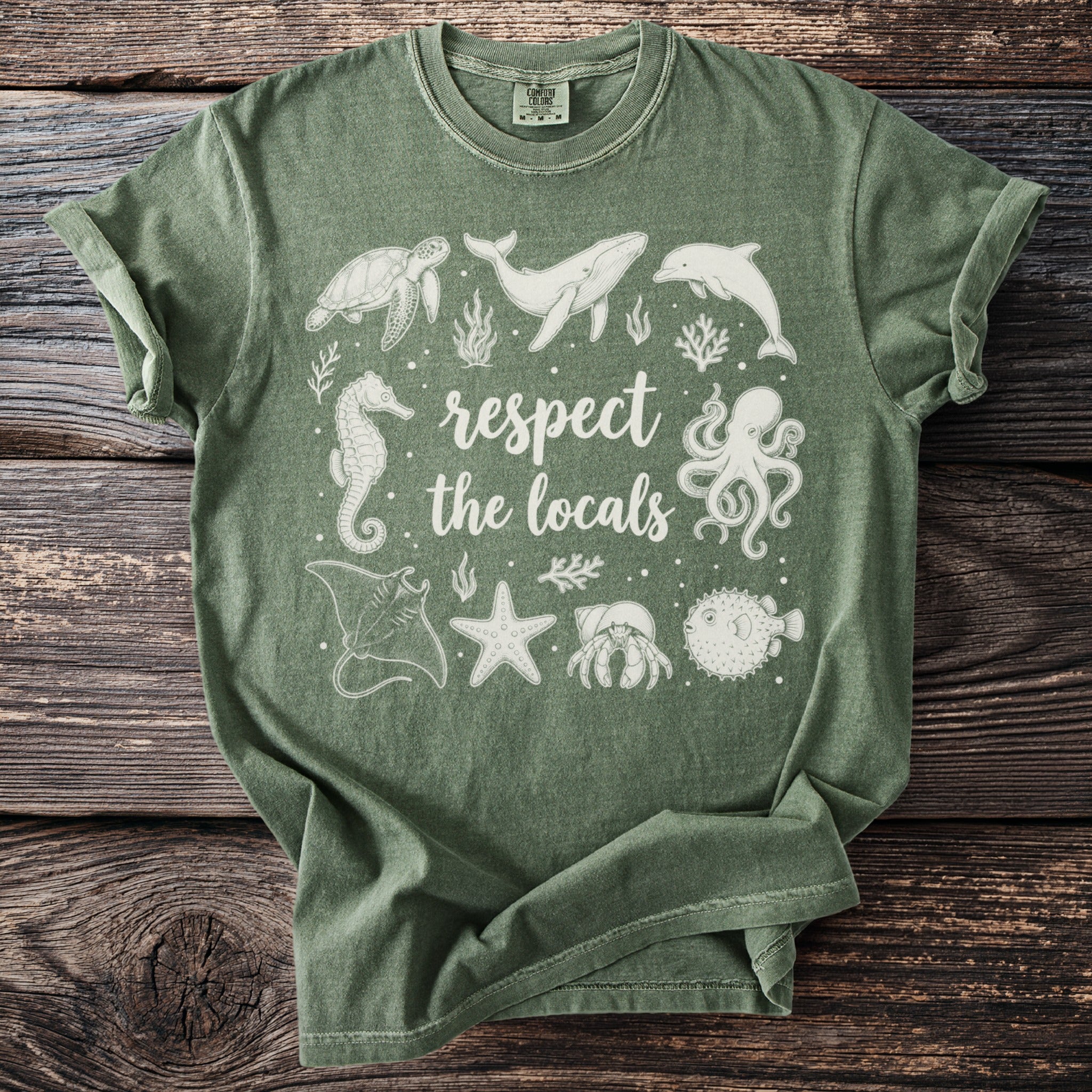 Green t-shirt with white ink art of sea creatures and text "respect the locals".