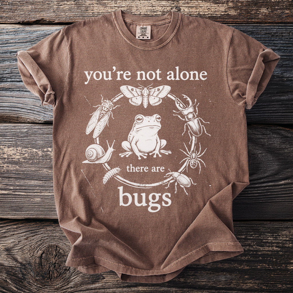 Brown t-shirt with text "you're not alone there are bugs" and insect illustrations.