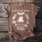 Brown t-shirt with text "you're not alone there are bugs" and insect illustrations.