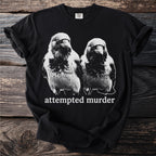 Black t-shirt with a graphic of two birds and the text "attempted murder".