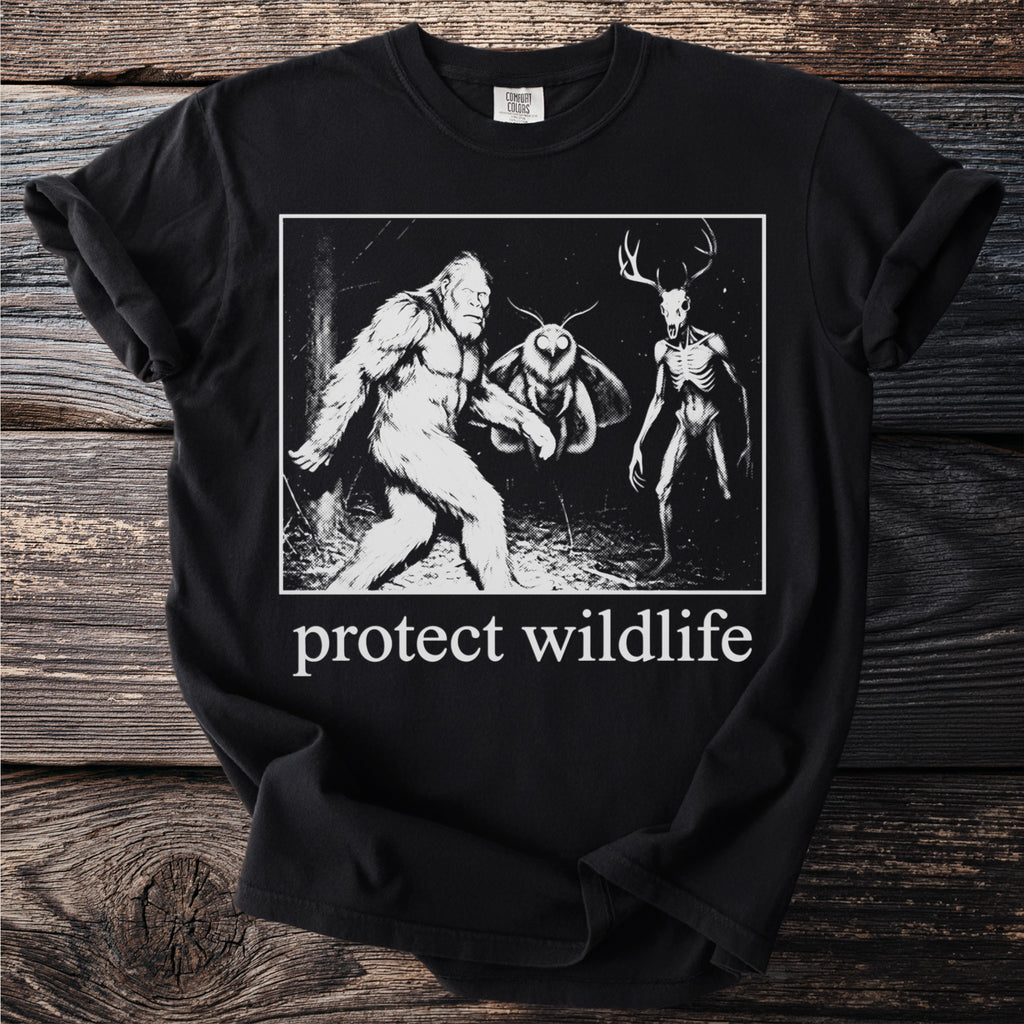 Black t-shirt with "protect wildlife" text and a graphic of Bigfoot, mothman, and a deer-headed skeleton.
