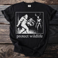 Black t-shirt with "protect wildlife" text and a graphic of Bigfoot, mothman, and a deer-headed skeleton.