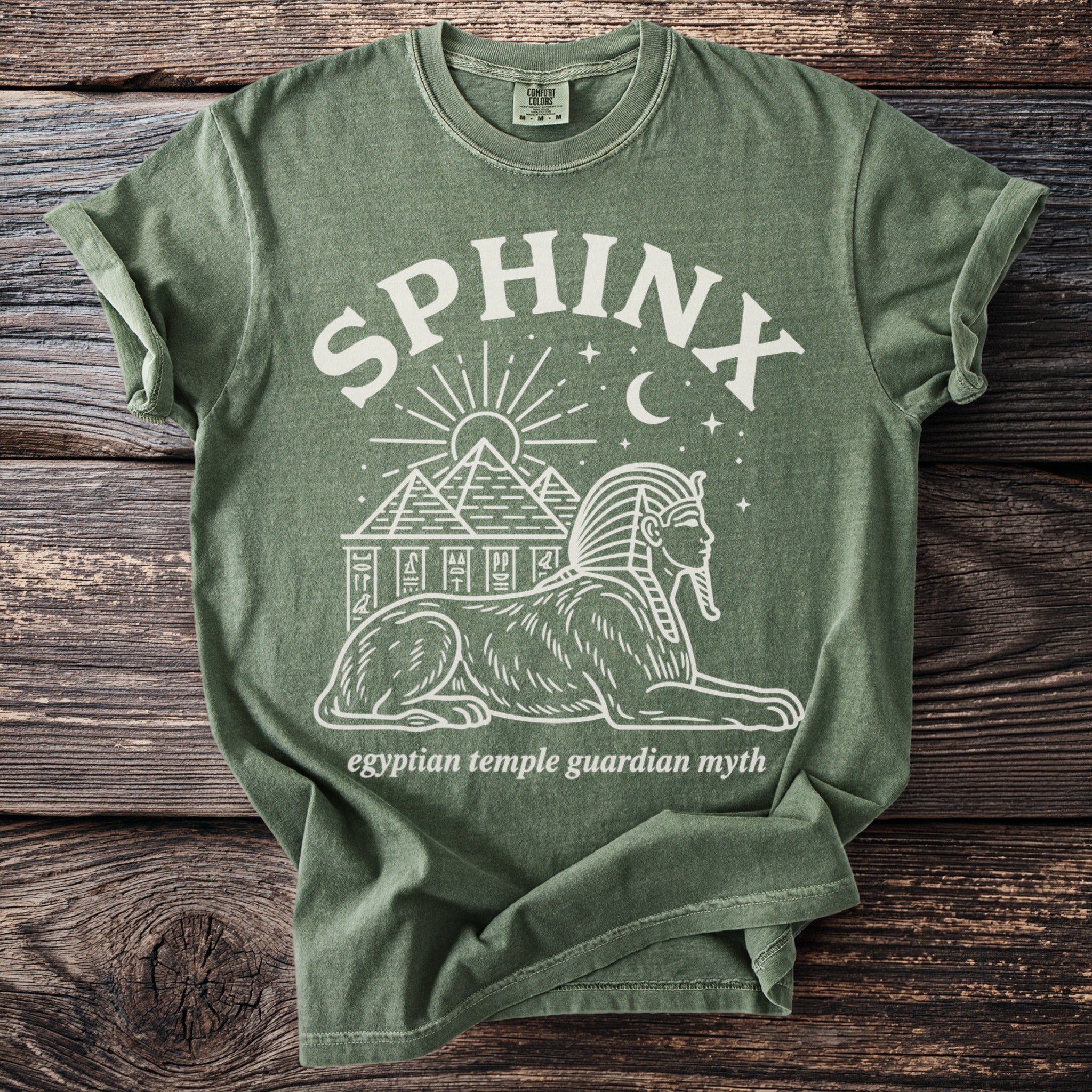 Olive green t-shirt with white sphinx, pyramids, sun, moon, and stars graphic.