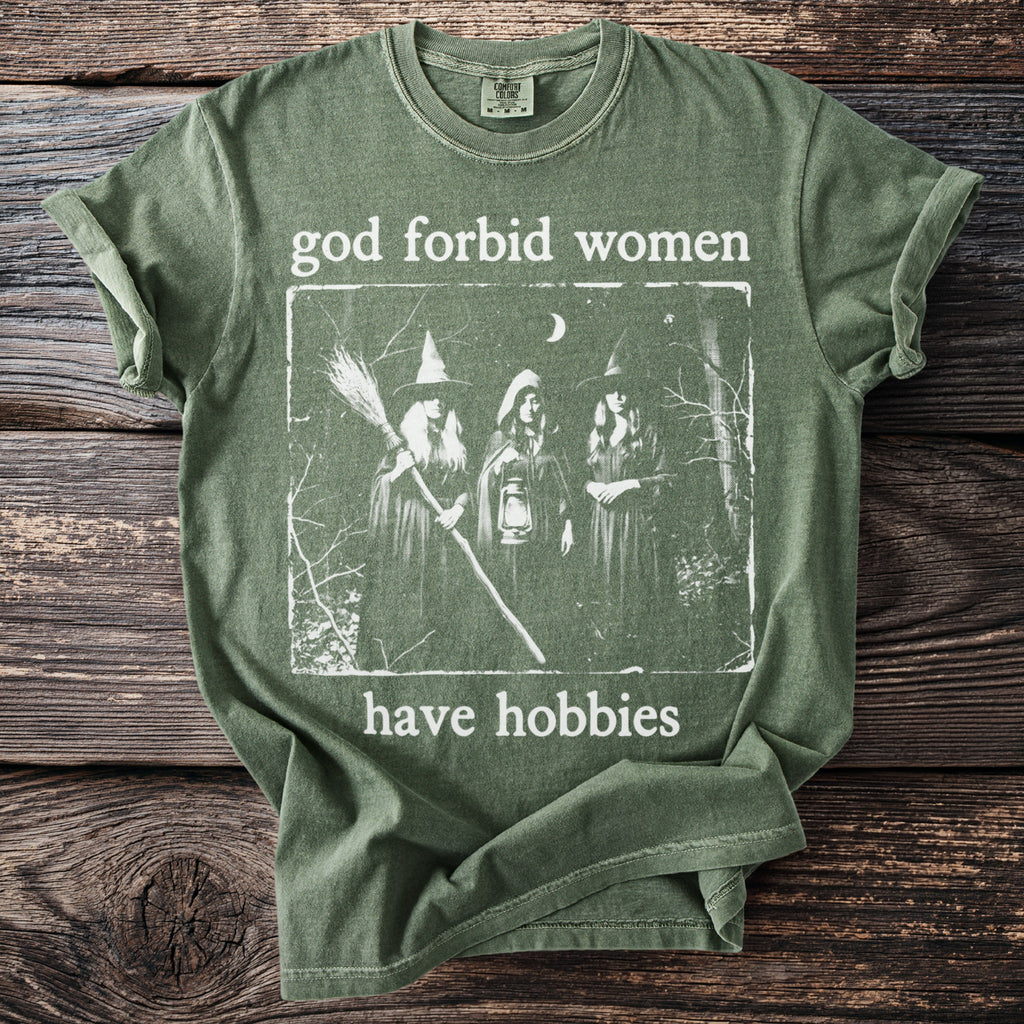 Green t-shirt with "god forbid women have hobbies" and three witches graphic.