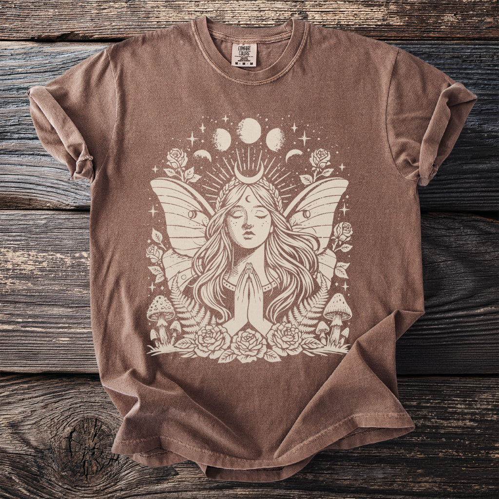 Brown t-shirt with a cream graphic of a winged fairy, crescent moon, and celestial elements.