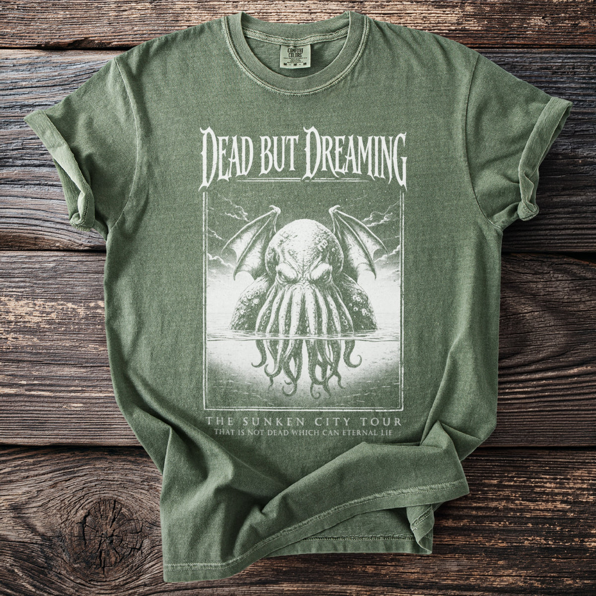 Green t-shirt with "DEAD BUT DREAMING" and tentacled creature graphic.