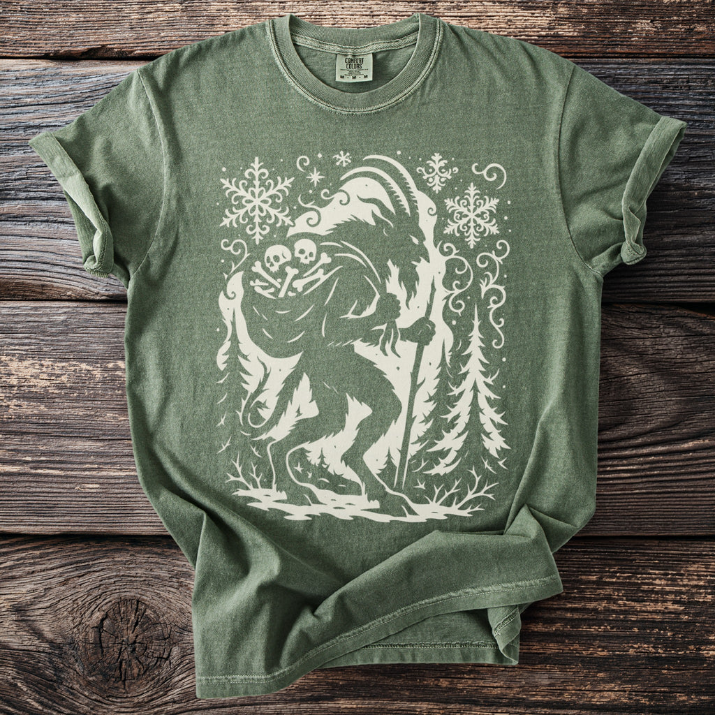 Green t-shirt with a cream Krampus silhouette carrying a sack and a staff among fir trees.