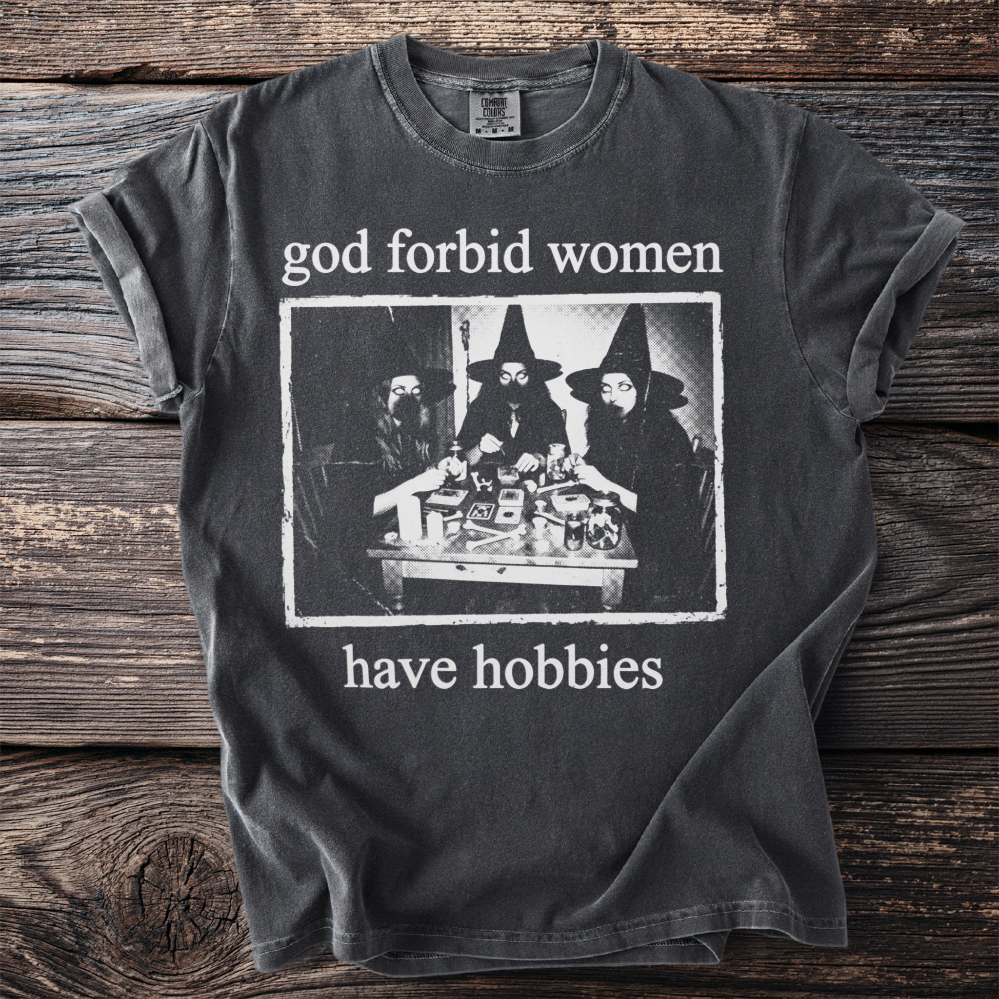 Dark grey t-shirt with black and white graphic "god forbid women have hobbies".