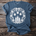 Blue t-shirt with a rose and candle wreath graphic featuring "Memento Mori" ornaments.