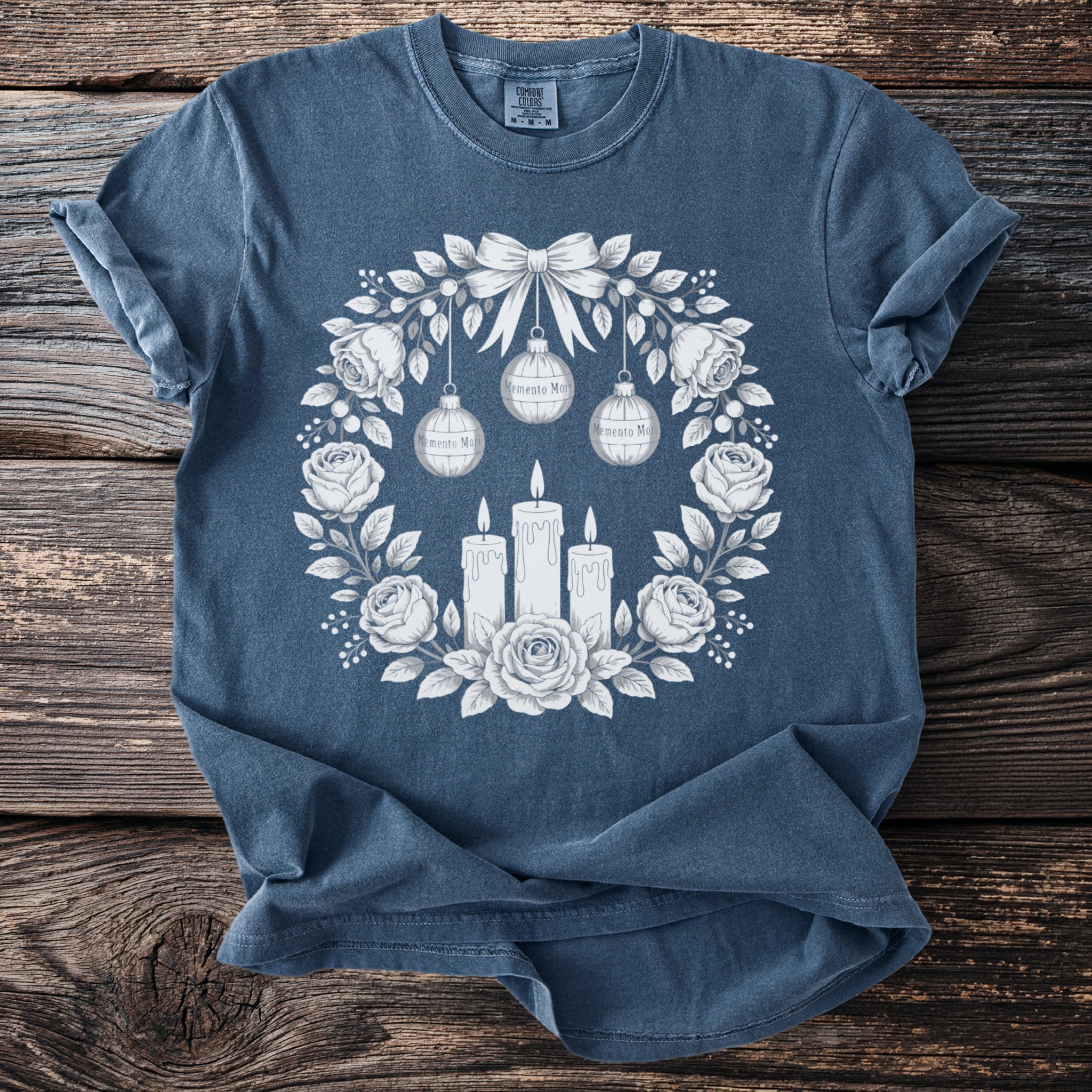 Blue t-shirt with a rose and candle wreath graphic featuring "Memento Mori" ornaments.