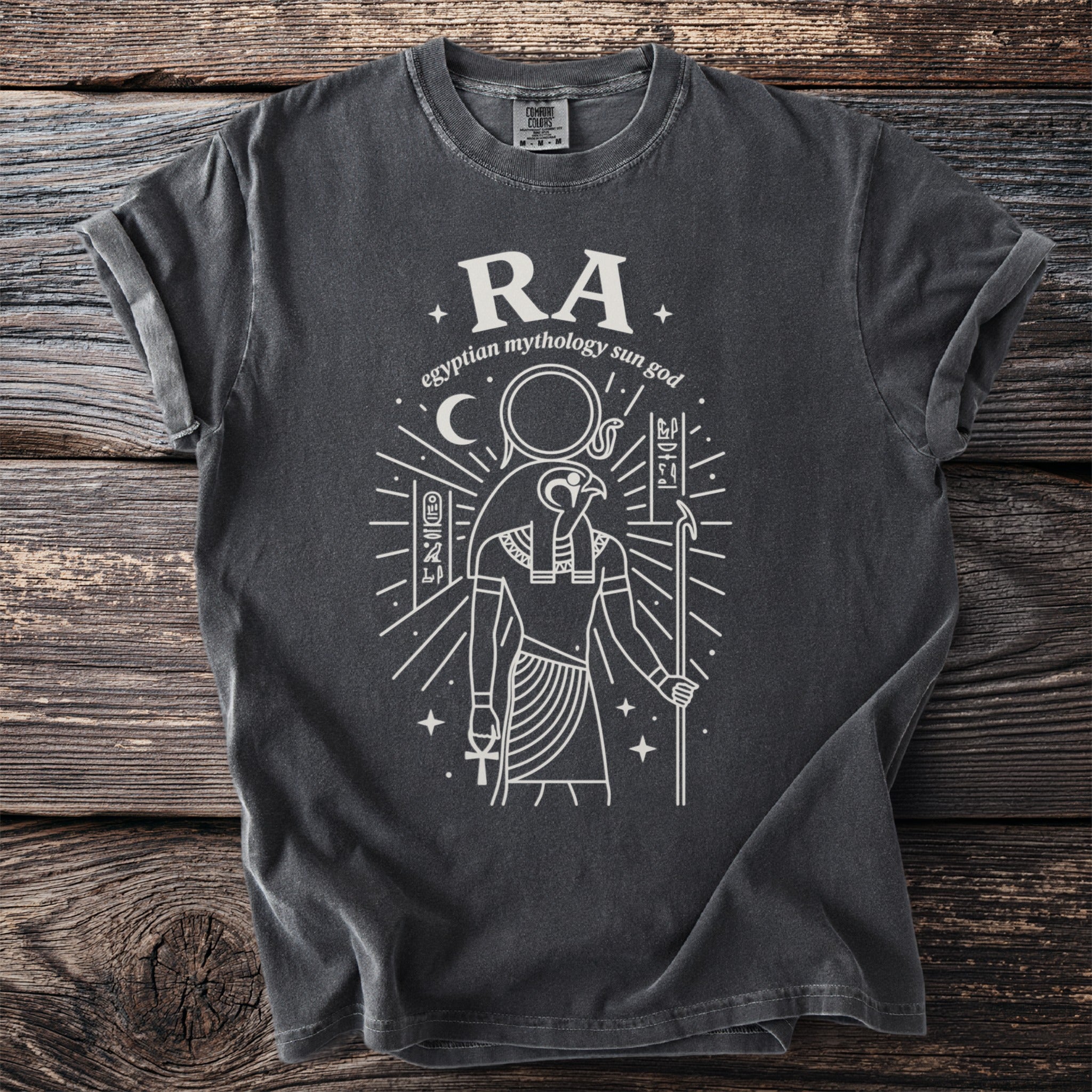 Dark grey t-shirt with white line art of Egyptian sun god Ra, moon, and hieroglyphs.
