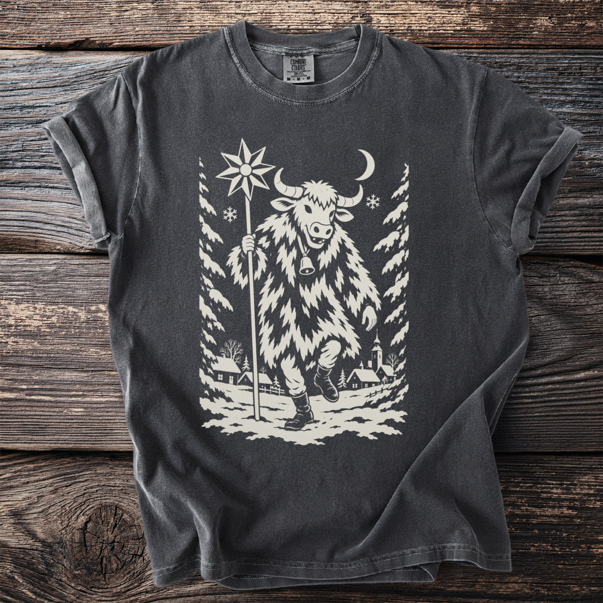 Pepper gray t-shirt with a cream folk-cut print: a bull-masked figure in a shaggy coat walks through a snowy village carrying a star on a pole.