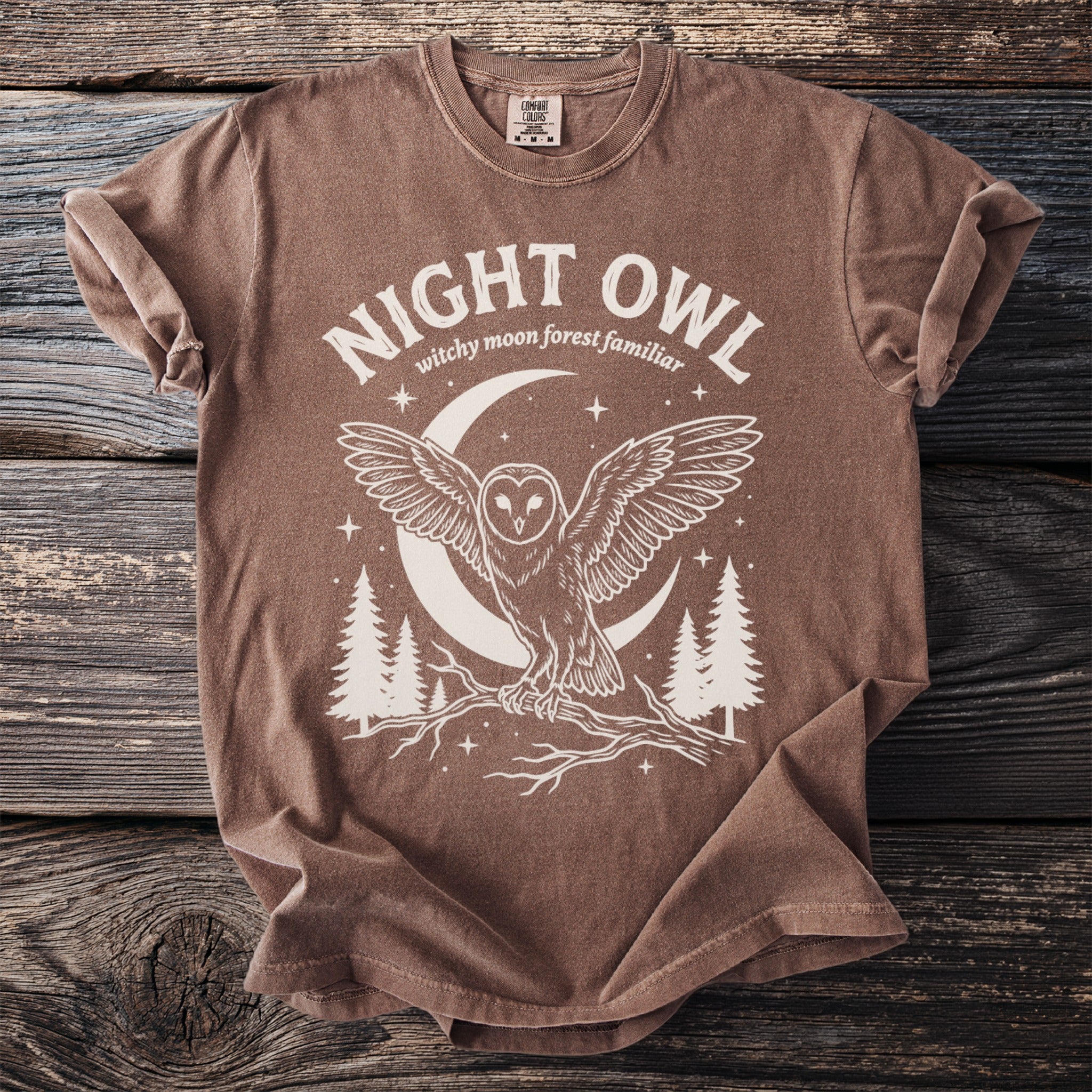 Brown t-shirt with white text "NIGHT OWL" above owl on branch with moon and trees.