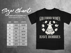 Black t-shirt with text "God Forbid Women Have Hobbies" and size chart.