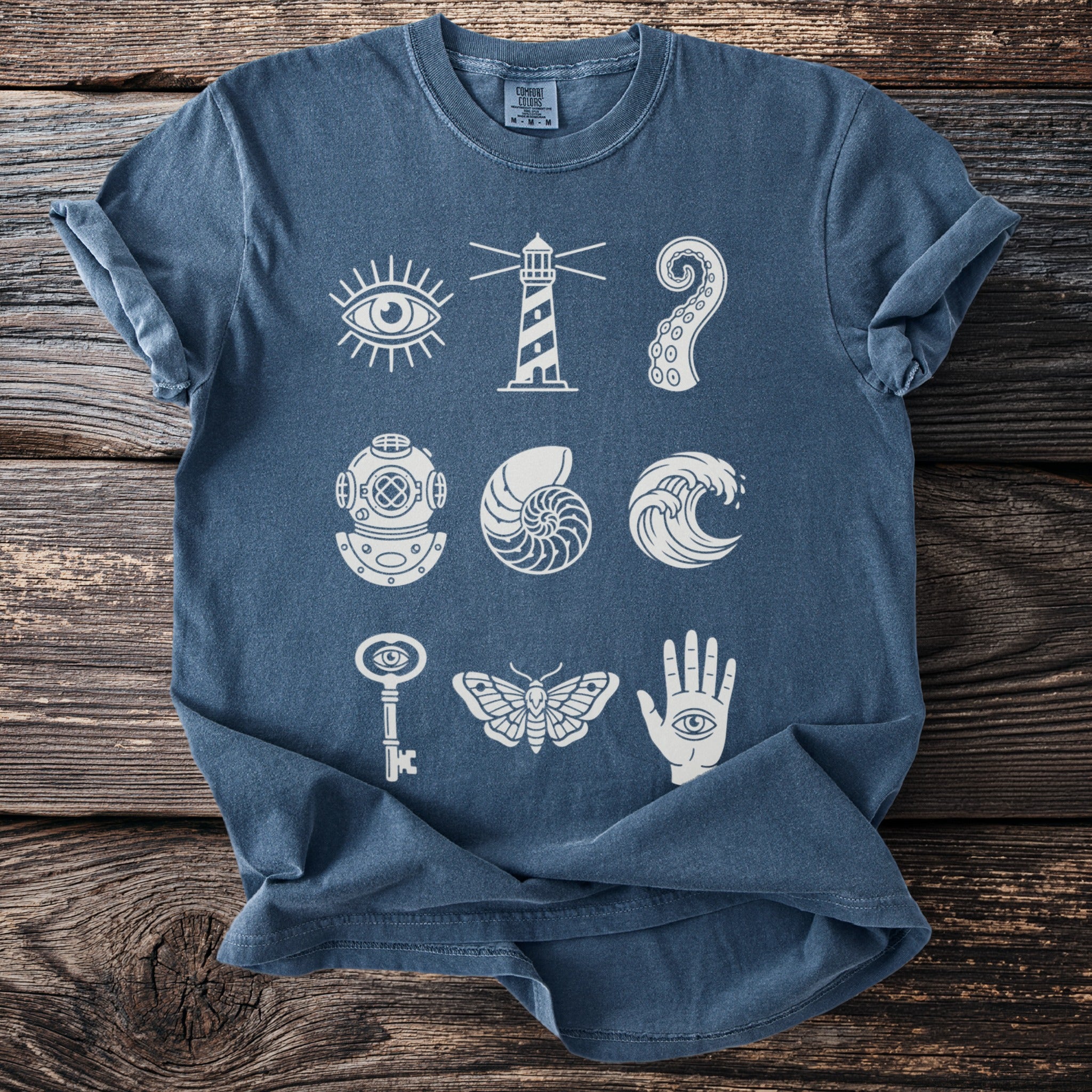 Blue t-shirt with white nautical and mystical graphic icons arranged in a grid.