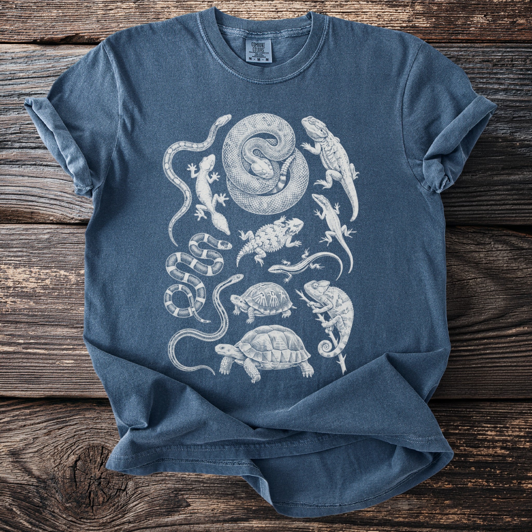 Blue t-shirt with white graphic of various reptiles including snakes and turtles.