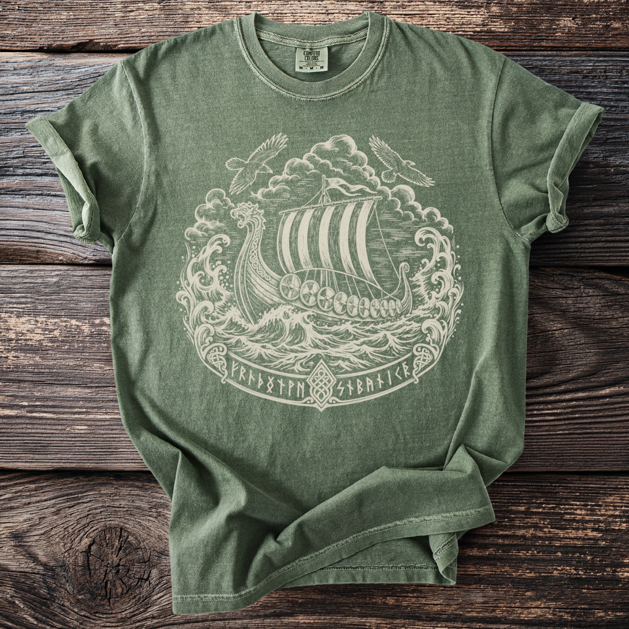 Green t-shirt with white Viking ship, stormy seas, two birds, and runes design.