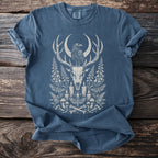 Blue t-shirt with white graphic of deer skull, raven, crescent moon, and botanical elements.