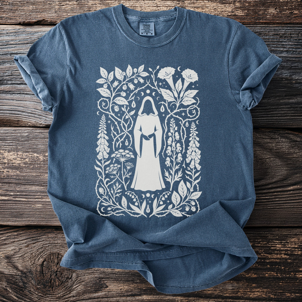 Blue t-shirt with white graphic of cloaked figure surrounded by floral and celestial designs.