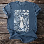 Blue t-shirt with white graphic of cloaked figure surrounded by floral and celestial designs.