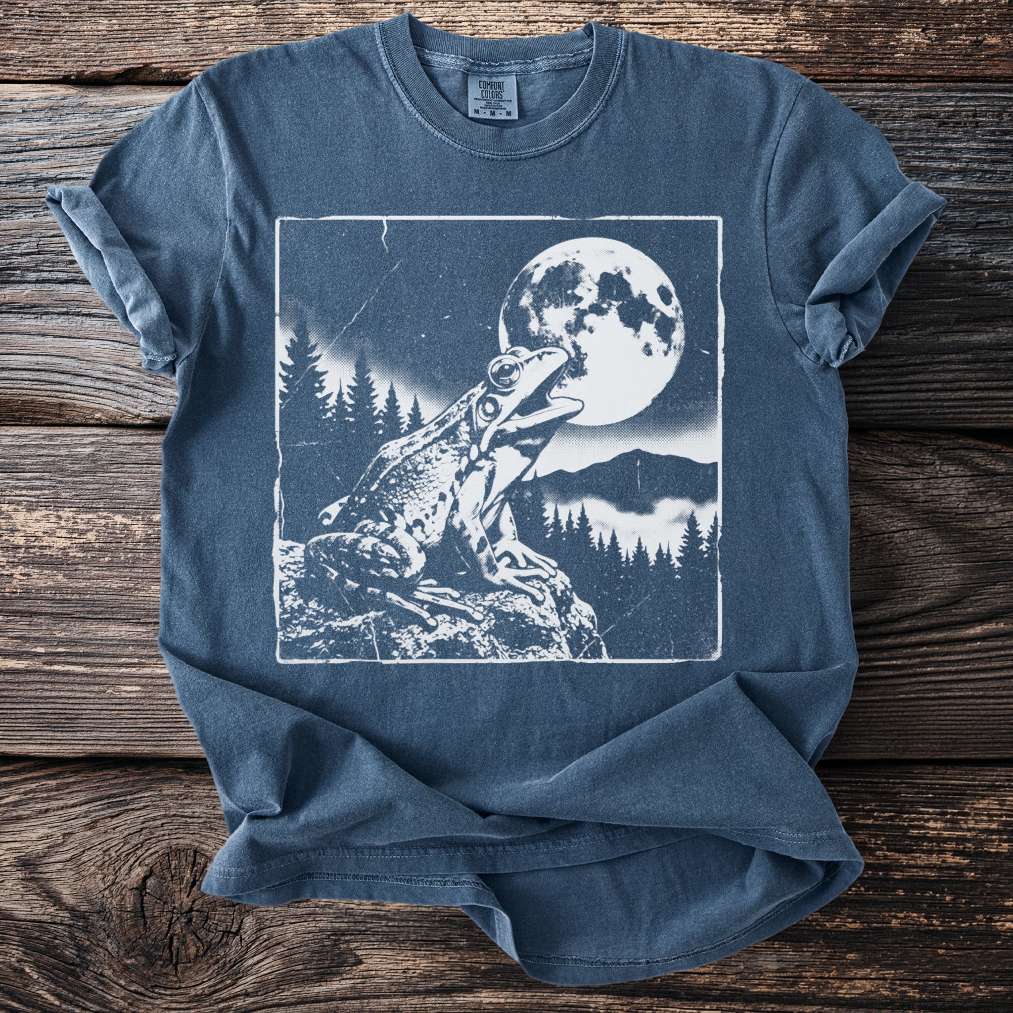 Frog croaking under a full moon with trees and mountains on a t-shirt.