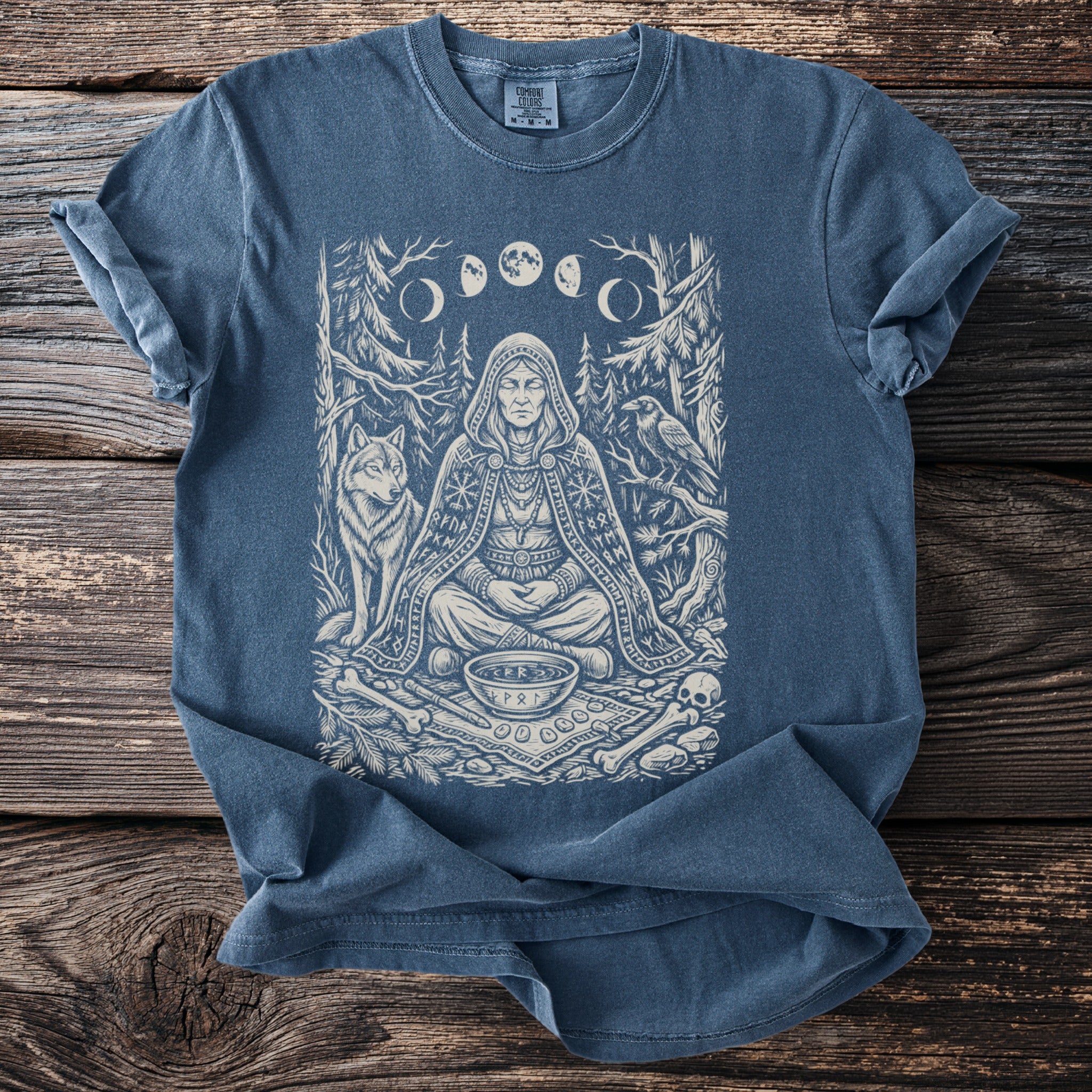 T-shirt with a graphic of a meditative figure, wolf, crow, and moon phases.