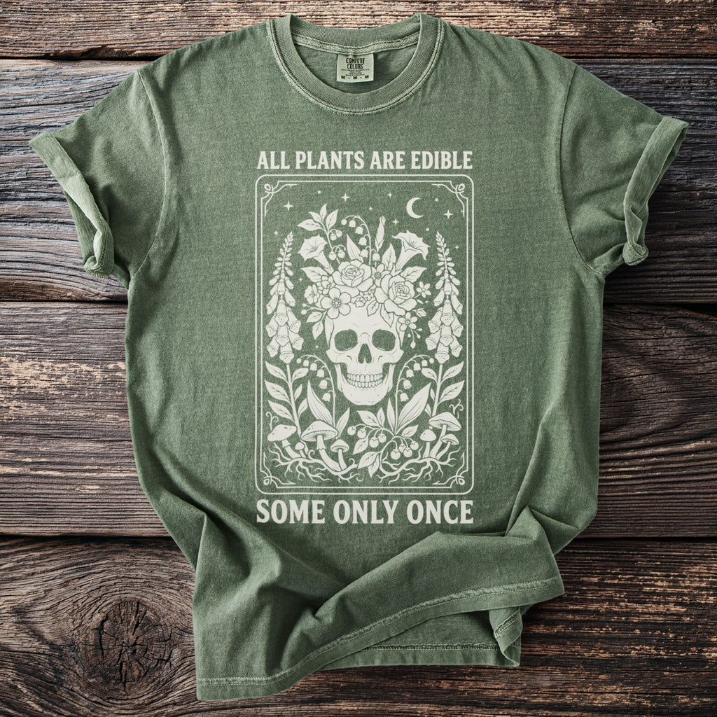 Green t-shirt with skull and floral graphic, reading "All Plants Are Edible Some Only Once".