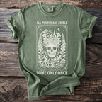 Green t-shirt with skull and floral graphic, reading "All Plants Are Edible Some Only Once".