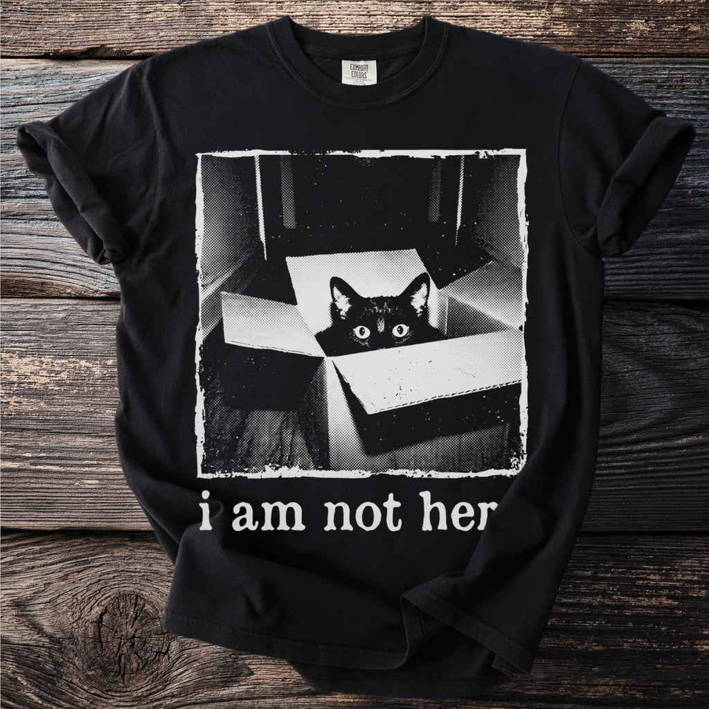 Black t-shirt with a black cat peeking out of a box and text "i am not her".
