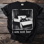 Black t-shirt with a black cat peeking out of a box and text "i am not her".