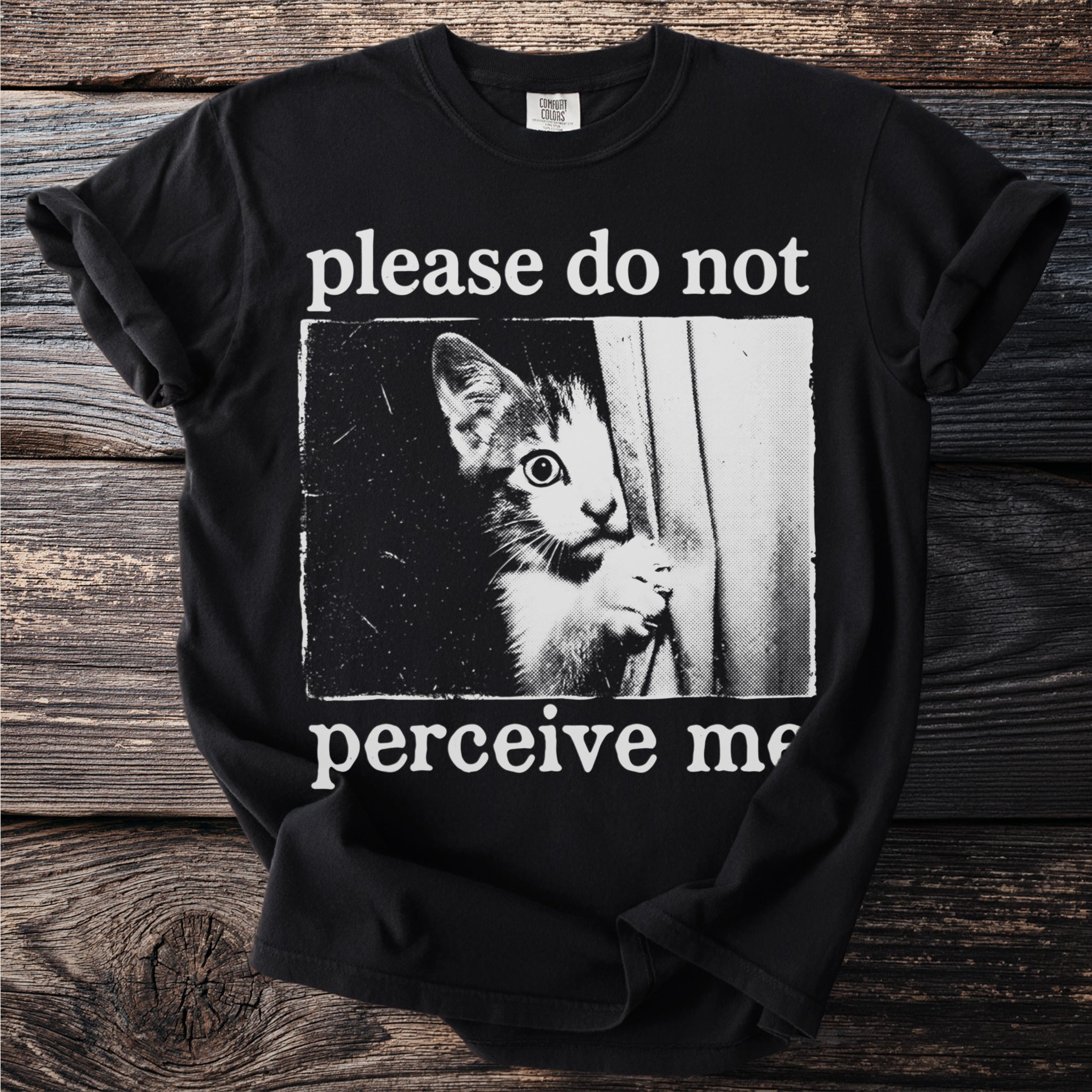 Black t-shirt with a vintage-style graphic of a kitten peeking and the text "please do not perceive me."