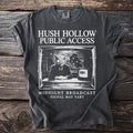 Dark gray t-shirt with "Hush Hollow Public Access" and owl news anchor graphic.