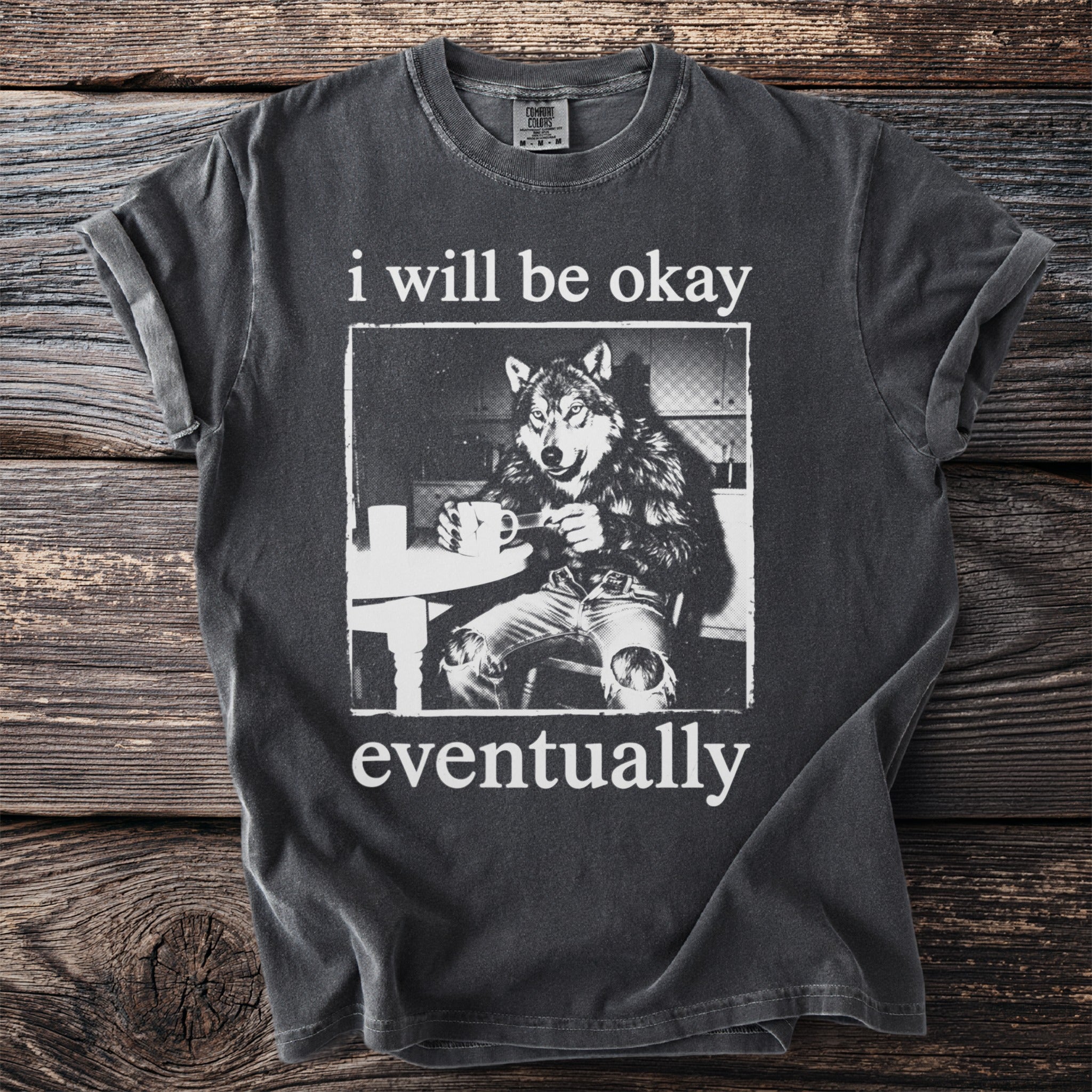 Dark t-shirt with wolf illustration and text "i will be okay eventually."