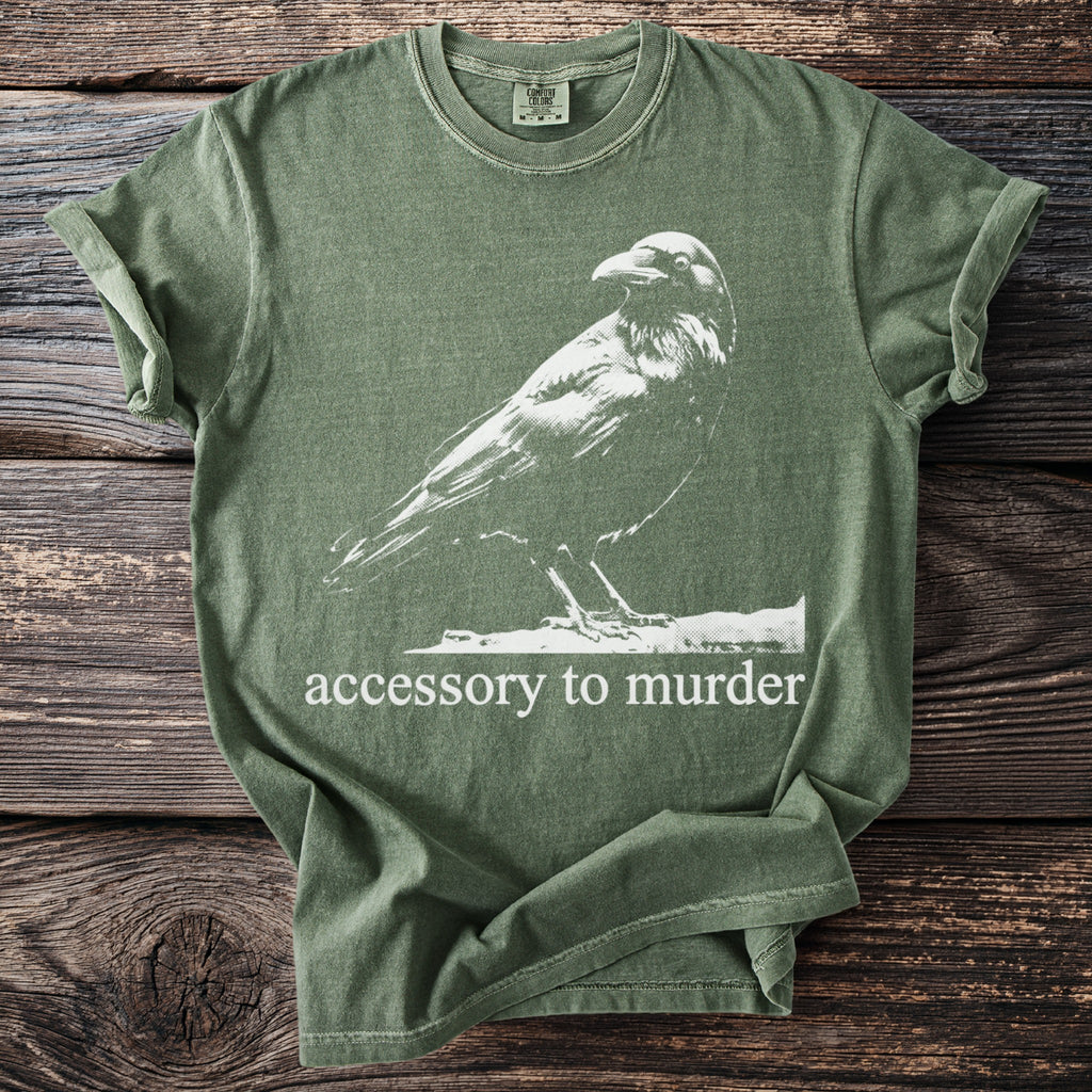 Green t-shirt with white raven graphic and "accessory to murder" text.