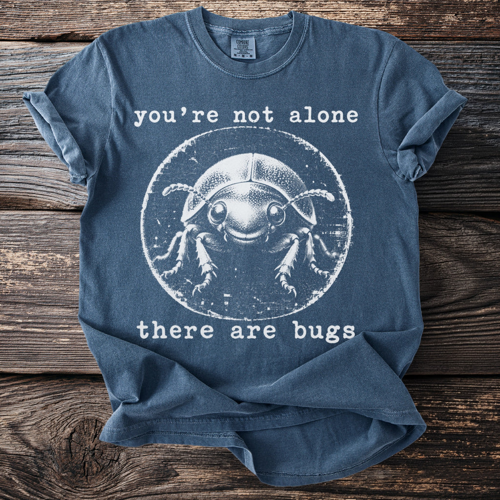 Blue t-shirt with graphic of a smiling beetle and text "you're not alone there are bugs".