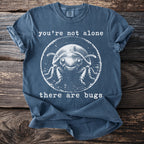 Blue t-shirt with graphic of a smiling beetle and text "you're not alone there are bugs".