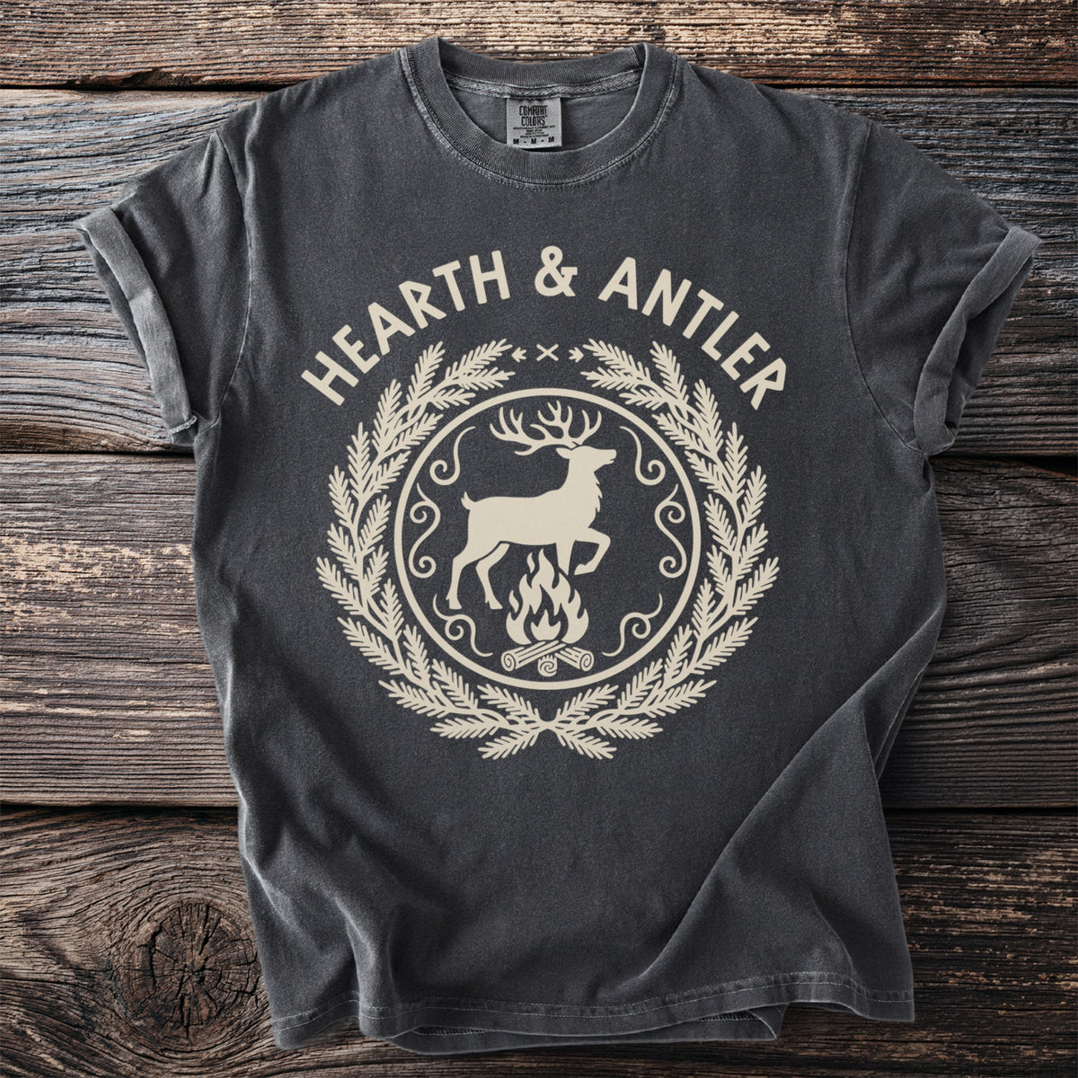 Dark gray t-shirt with "HEARTH & ANTLER" above a deer and campfire emblem.