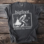 T-shirt with Bigfoot at a campfire grilling a hot dog and text "bigfoot grabbed my weiner".