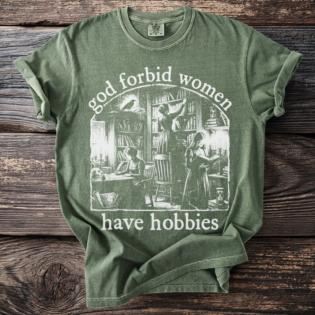 Green t-shirt with "god forbid women have hobbies" text and vintage library illustration.