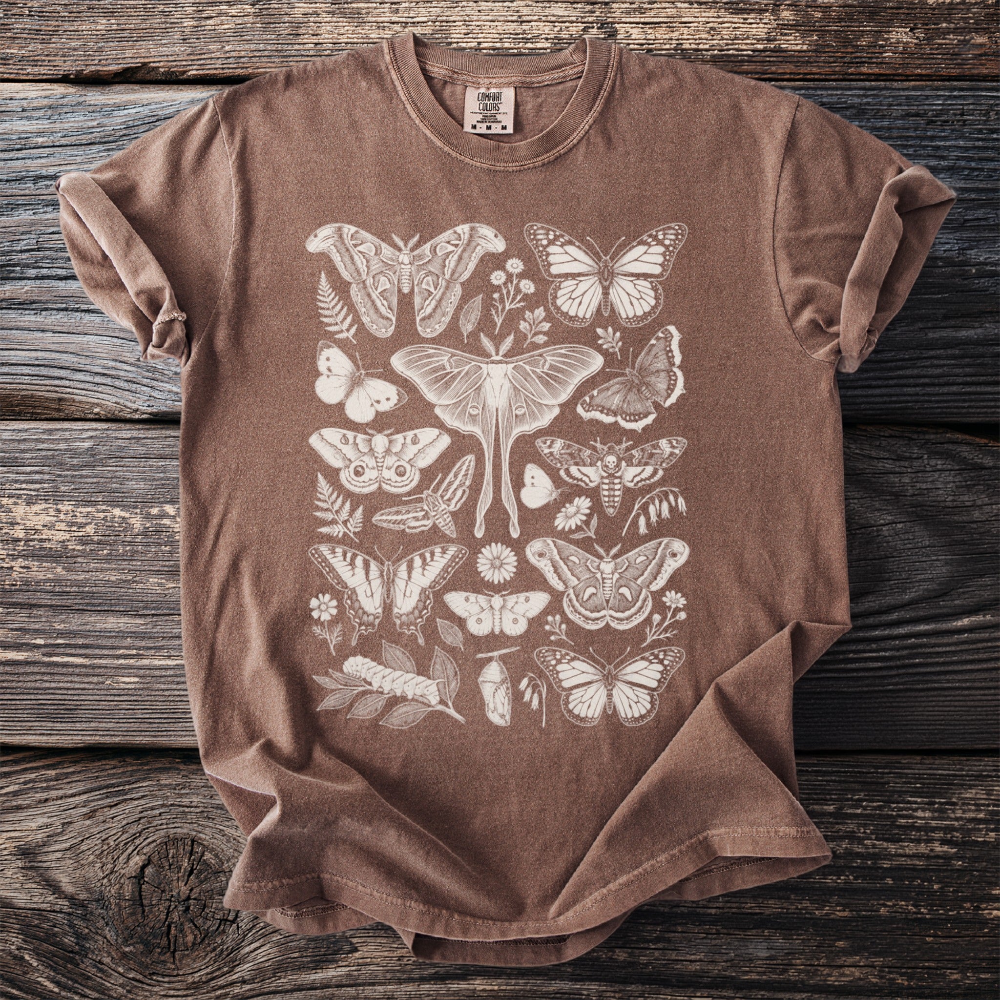 Brown t-shirt with an off-white detailed print of various moths, butterflies, leaves, and flowers.