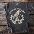 Dark t-shirt with "GUARDIED BY RAVENS" text, a raven on a triangle, and oak leaves.