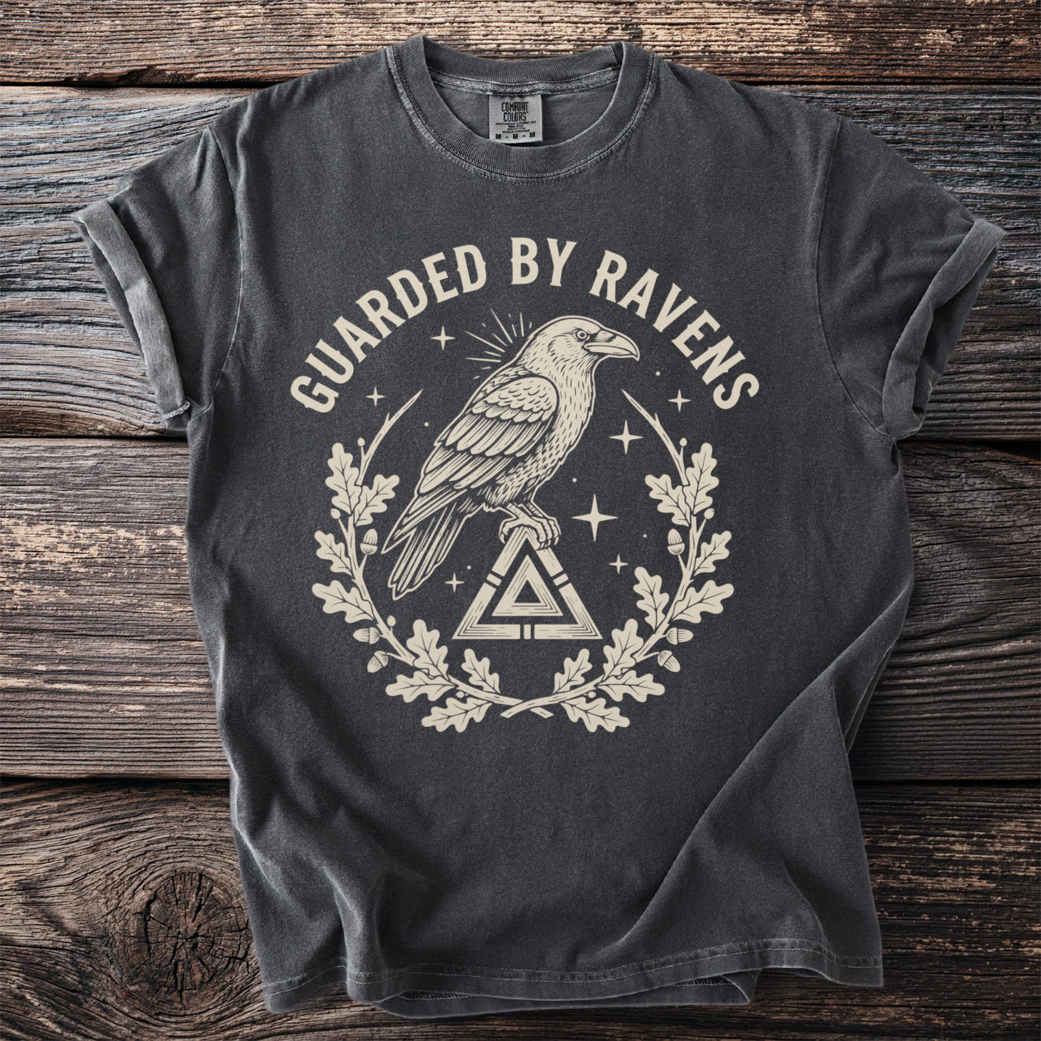 Dark t-shirt with "GUARDIED BY RAVENS" text, a raven on a triangle, and oak leaves.